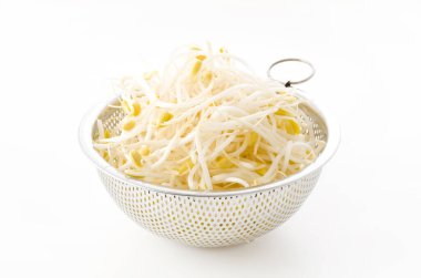 Beyaz arka planda paslanmaz çelikten kevgire dönüşen soya fasulyesi.