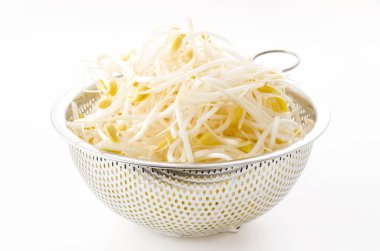 Beyaz arka planda paslanmaz çelikten kevgire dönüşen soya fasulyesi.