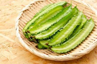 Tahta bir arka planda bambu elek üzerinde taze kanatlı fasulyeler.