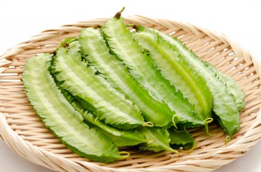 Beyaz arka planda bambu elek üzerinde taze kanatlı fasulyeler.