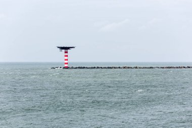 Kırmızı ve beyaz çizgili deniz feneri ile Hollanda Rotterdam liman girişinde heliplatform. Deniz feneri bir iskele beton dalga kesiciler ile sonunda bulunmaktadır.