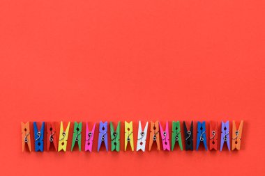 Renkli ahşap clothespins kırmızı bir arka plan ve kopya alanı üzerinde bir dizi.