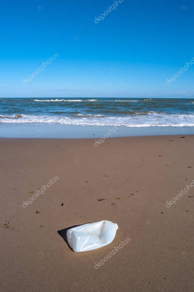 Plastic bottle in front of beautiful beach and ocean, plastic pollution in oceans
