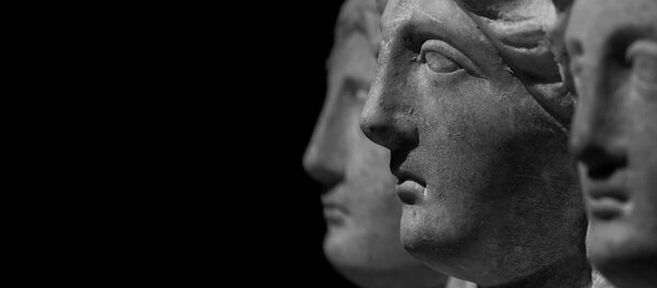 Мраморные древние разные головы как человечество на изолированном черном фоне
