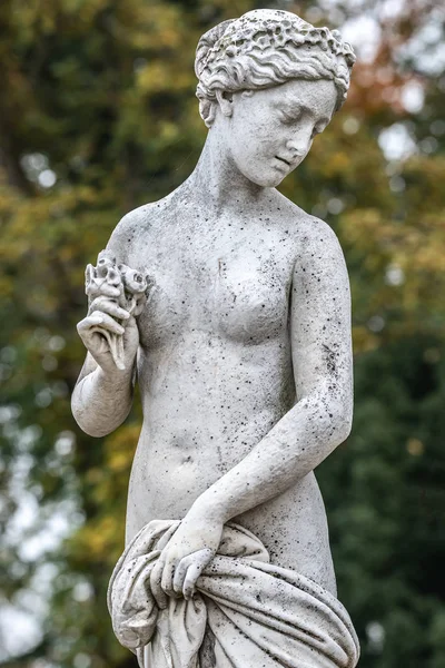 Statue of sensual naked Greek renaissance era woman with flowers