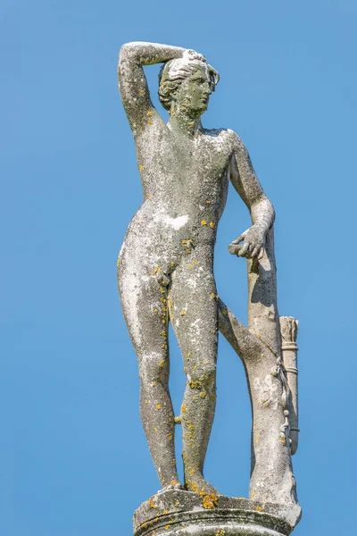 Antigua estatua cubierta de musgo y liquen de un cazador desnudo en — Foto de Stock