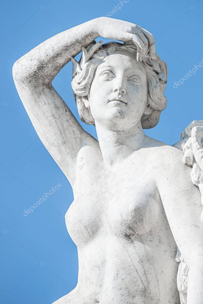 Old statue of sensual renaissance era woman at blue smooth backg