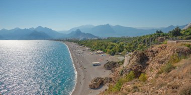 Antalya 'nın modern kısmı, Akdeniz kıyısı ve turistlerle dolu uzun çakıl taşı plajı, Antalya, Türkiye, güneşli gün, mavi gökyüzü üzerine panoramik kuş manzarası