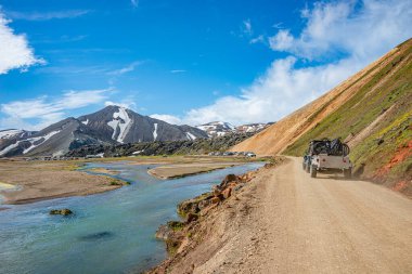 Büyük kavşak yolu 4WD otomobili, her sezon binlerce turist ve yürüyüşçünün bulunduğu renkli Landmannalaugar dağlarında büyük bir kamp alanında dağ bisikletleri taşıyor.