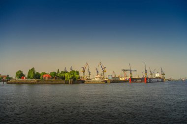 Sıcak günbatımında Hamburg limanında birçok konteynır vinci bulunan modern kargo limanı, Almanya, yaz