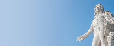 Güneşli bir günde Viyana 'nın tarihi şehir merkezinde Mozart anıtı bulunan bayrak, metin için metin alanı olan mavi gökyüzü