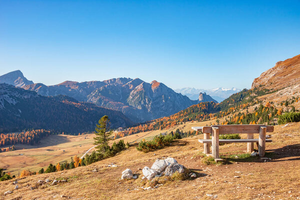 Panorama over Dolomites at Three Peaks (Tre Cime, Drei Zinnen) and Fanes-Sennes-Prags National Parks during sunset and golden Autumn with a bench to relax after hiking, South Tyrol, Italy
