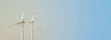 Elektrik enerjisi üretmek için büyük rüzgar türbinleri, mavi gökyüzünde yeşil eko-dostluk enerjisi, günbatımı sıcak renkler ve metin alanı için fotokopi alanı