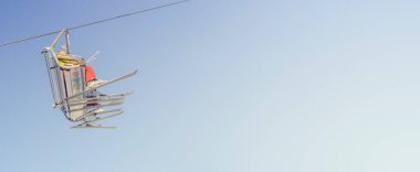 Kayak asansöründe büyük bir kayakçı grubuyla gün batımında mavi ve sarı bir kayak merkezinde yokuş yukarı ilerlerken metin için fotokopi alanı ile günbatımında temiz bir gradyan gökyüzü