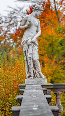 Şehirli, yarı çıplak Yunan ya da İtalyan Rönesans döneminin heykeli. Şehir parkında çiçekli kadın Golden Autumn, Potsdam, Almanya 'ya gitti.