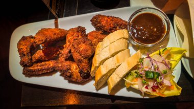 Alman usulü ızgara tavuk kanadı, barbekü sosu, ekmek ve salata.