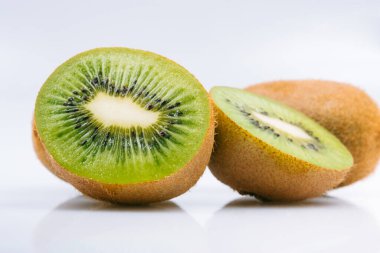 Olgun kivi meyvesi ve parlak arka planda yarım kivi meyvesi..