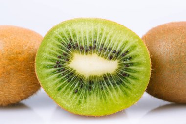 Olgun kivi meyvesi ve parlak arka planda yarım kivi meyvesi..