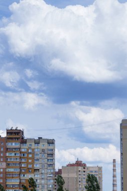 Bulutlu mavi gökyüzü ve binaların tepesinde devasa kümülüs bulutları..