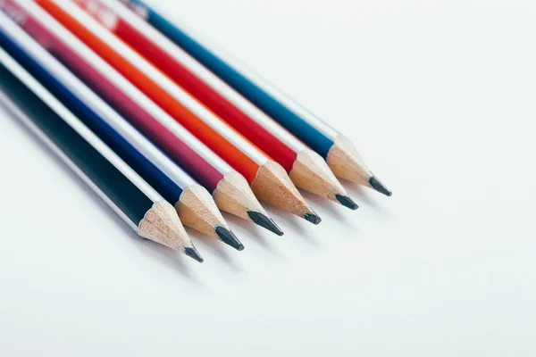 Multicolored wooden graphite pencils on light background.