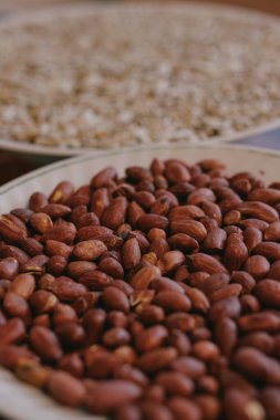 Ön planda bir tabakta kavrulmuş fıstık ve arka planda ayçekirdeği. Yakın plan..