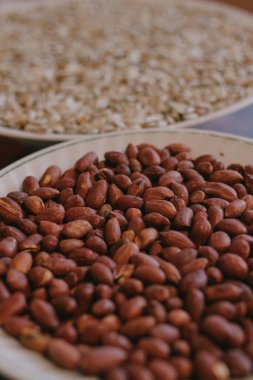 Ön planda bir tabakta kavrulmuş fıstık ve arka planda ayçekirdeği. Yakın plan..