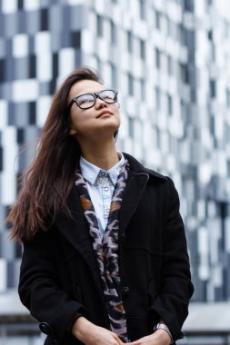 Dışarıda duran Asyalı güzel iş kadınının portresi. Arka planda bir gökdelen var..