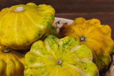 Hasır tabakta ahşap arka planda renkli pattypan kabağı. Kapat..