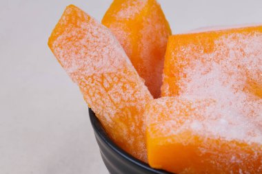 Masa örtüsündeki siyah kasede donmuş balkabağı parçaları..