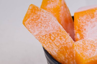 Masa örtüsündeki siyah kasede donmuş balkabağı parçaları..