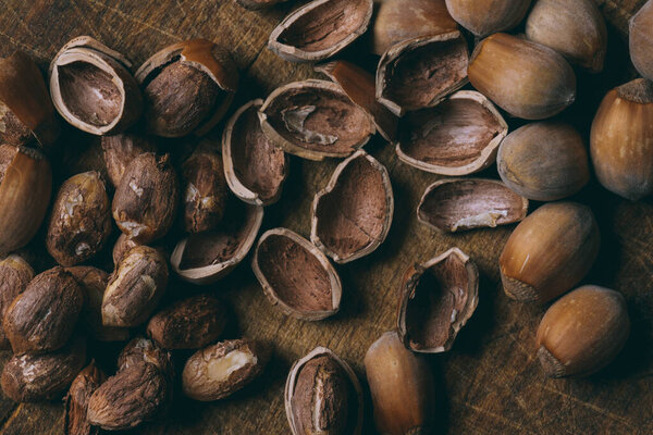 Whole nuts, shelled nuts and shells. Corylus avellana. Macro photo, close up, on wooden table. Top view.