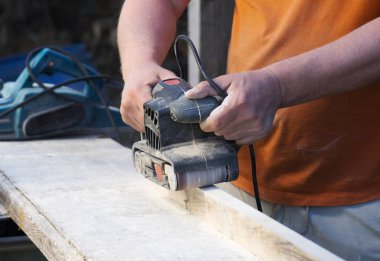 Açık havada elektrik sander makinasıyla tamirci.