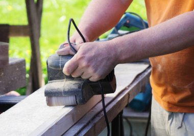 Açık havada elektrik sander makinasıyla tamirci.