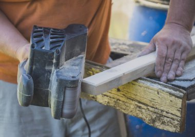 Açık havada elektrik sander makinasıyla tamirci.