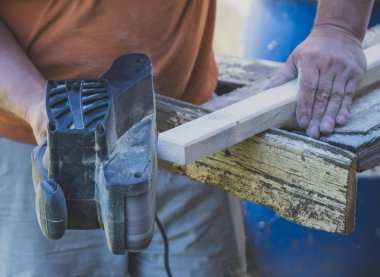 Açık havada elektrik sander makinasıyla tamirci.