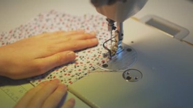 Küçük kız evde dikiş makinesi üzerinde çalışıyor. Yakın çekim görünümü.