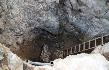 Merdiven ile derin bir çukurun içine iniş.