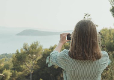 Kadın doğa cep telefonuyla çekiyor.