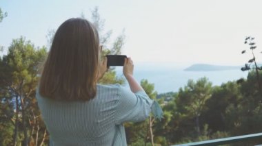 Kadın doğa cep telefonuyla çekiyor.