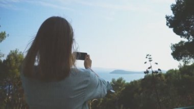 Kadın doğa cep telefonuyla çekiyor.