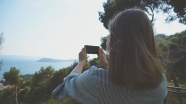 Kadın doğa cep telefonuyla çekiyor.