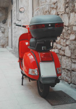 Kırmızı scooter boş sokakta park edilmiş..