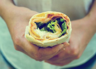 Jambon, peynir ve salata sandviç sarın tutan kadın.