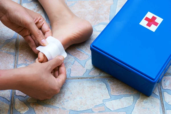 Woman puts adhesive bandage on child foot.