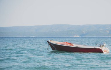 Açık denizde yalnız kırmızı tekne palamarla.