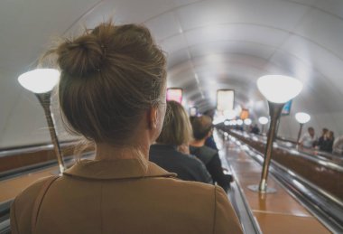 Metroda bir yürüyen merdiven kullanan kadın.