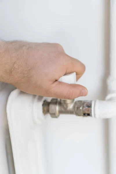 Мужская рука регулирует термостат, чтобы включить обогреватель радиатора дома . — стоковое фото