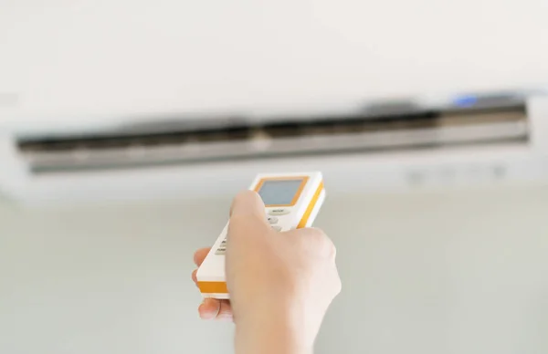 Mano que sostiene el mando a distancia dirigido al aire acondicionado . — Foto de Stock