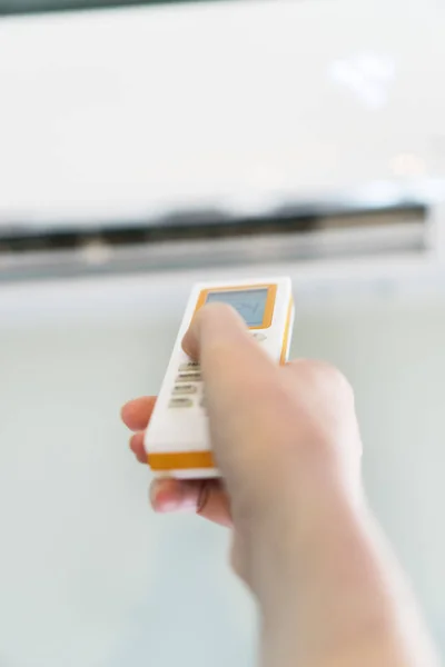 Hand holding remote control aimed at the air conditioner. — Stock Photo, Image