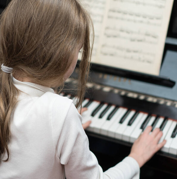 Little girl learning to play the piano.